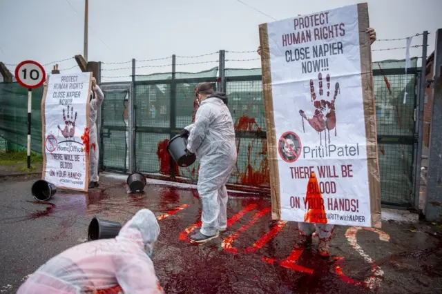 Protesters throw fake blood at the gates