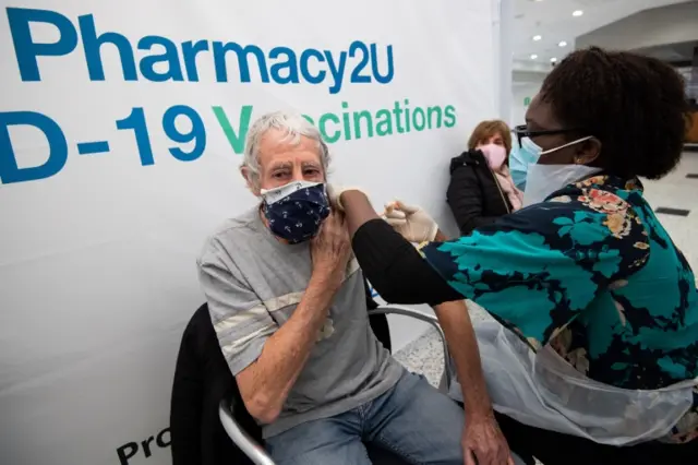 Lesley Mitchell, aged 75, from Newmarket, receives the Oxford/AstraZeneca vaccine, watched by his wife Janice at the opening of a Pharmacy2U Covid-19 vaccination centre, at the Newmarket Racecourse, Suffolk. Picture date: Saturday January 30, 2021