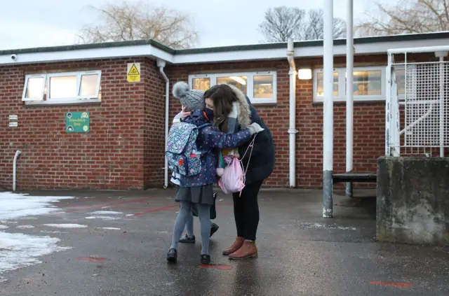 A parent hugs their child outside school