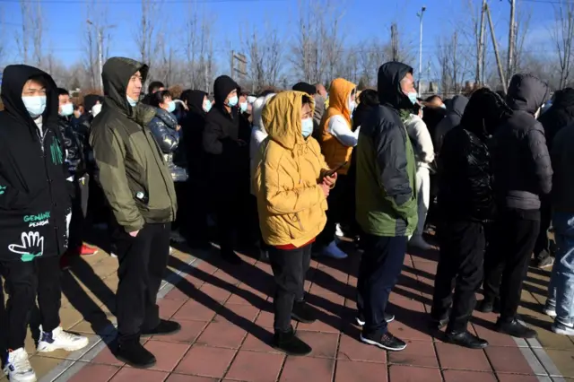 People wait to board shuttle buses to a Covid-19 coronavirus vaccine centre in Beijing