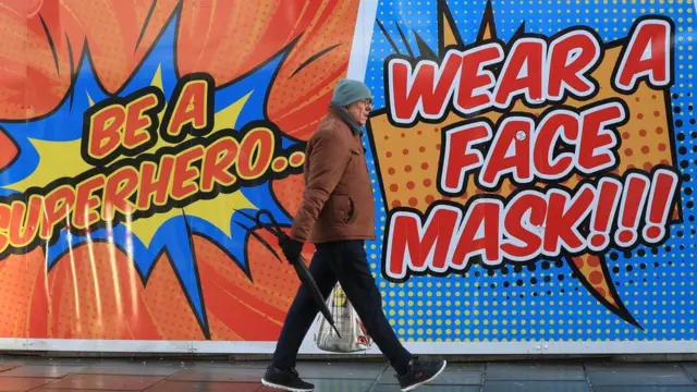 A man walking past a coronavirus sign