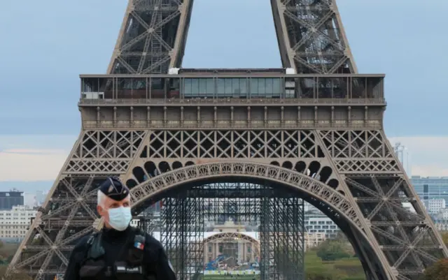 Police officer stands in front of Eiffel Tower