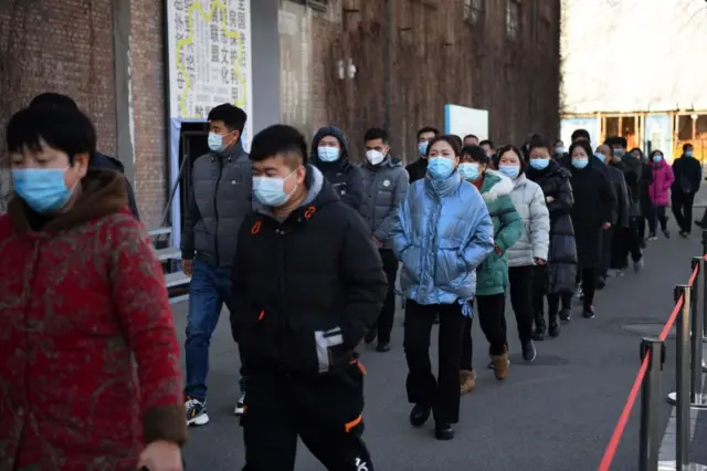 People wait to board shuttle buses to a COVID-19 coronavirus vaccine center in Beijing