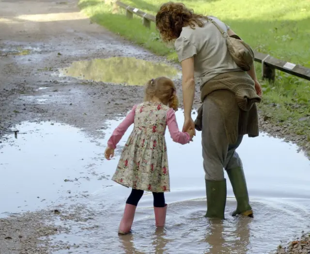 A mother and daughter walking through a puddle