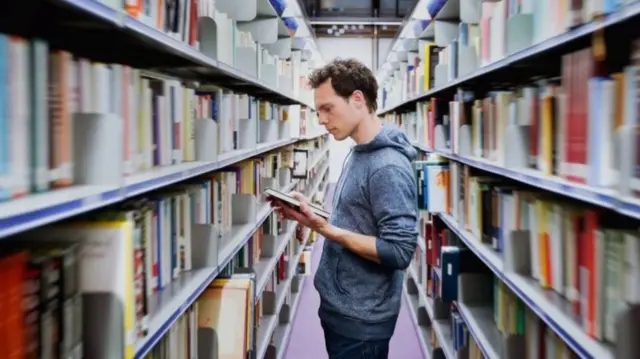 A man looks at a book in a library