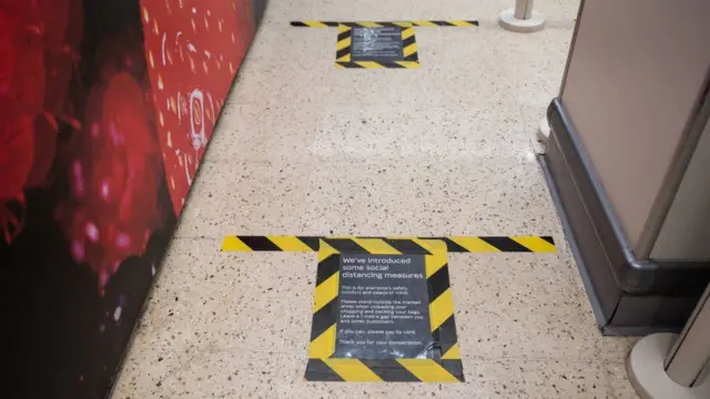 Social distancing sign on floor of supermarket during March lockdown