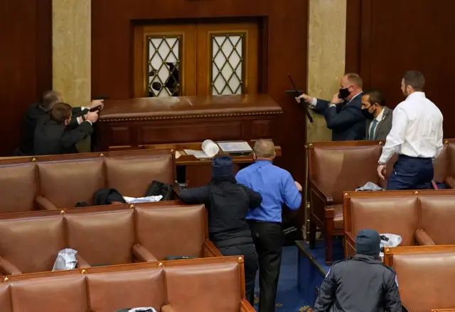 Capitol police officers point their guns at a door that was vandalized in the House Chamber during a joint session of Congress on January 06, 2021 in Washington, DC