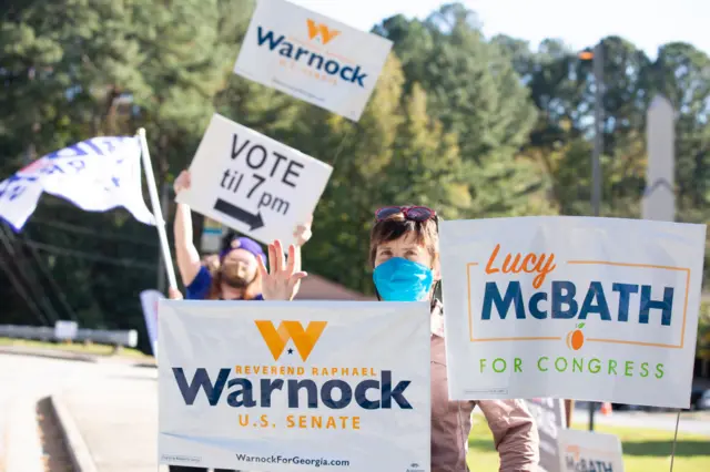 Lisa Guyton waves campaign signs near an entrance to a Dekalb county poll location on November 3, 2020 in Atlanta, Georgia