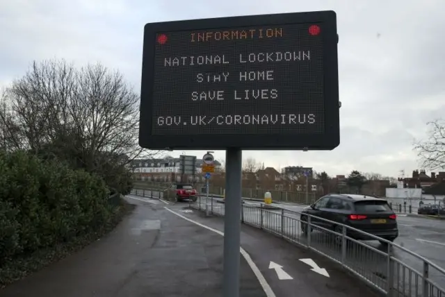 Cars pass a information sign notifying people about the national lockdown