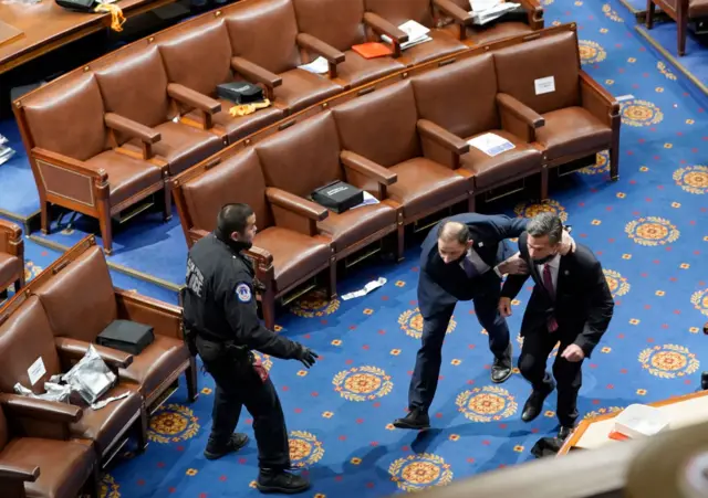 Members of congress run for cover as protesters try to enter the House Chamber during a joint session of Congress on January 06, 2021 in Washington, DC