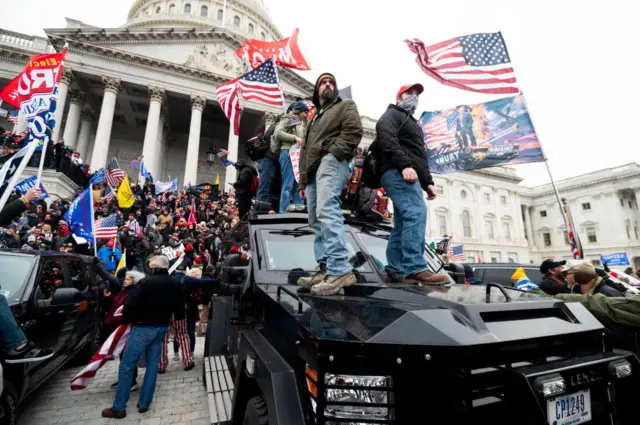 Trump supporters stand on the US Capitol Police armoured vehicle as others take over the steps of the Capitol on Wednesday, Jan. 6, 2021, as the Congress works to certify the electoral college votes