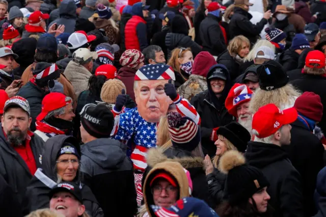 A Trump supporter wears a mask of the president's face