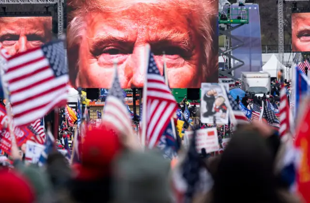 An image of President Donald Trump appears on video screens before his speech to supporters from the Ellipse at the White House in Washington