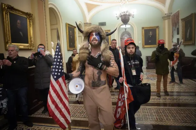 A man wearing face paint shouts as he makes his way to the Senate Chamber.