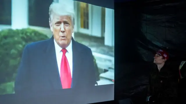 Person watches Donald Trump on a large screen January 6, 2021 in Salem, Oregon.