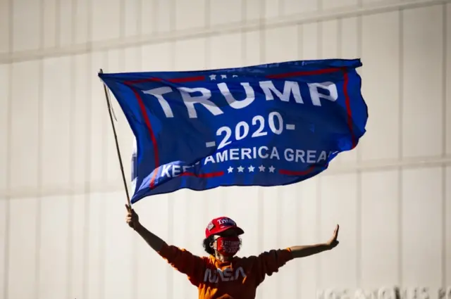 A person holds a Trump 2020 flag