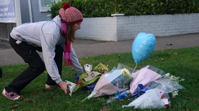 A woman lays flowers near the scene