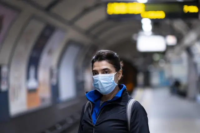 A woman wearing a mask on the tube