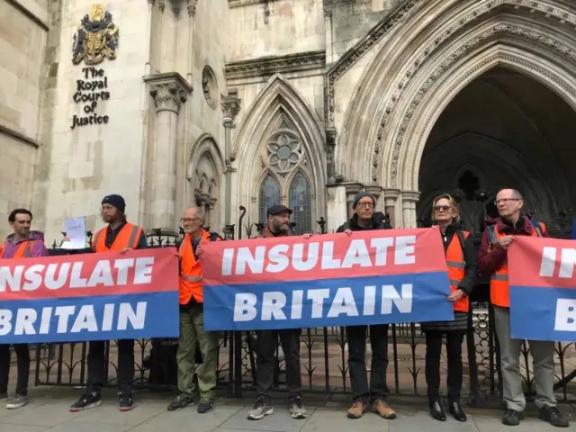 Climate change demonstrators from Insulate Britain hold banners outside the Royal Courts of Justice in London,