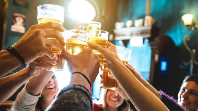 People toasting pints in a pub