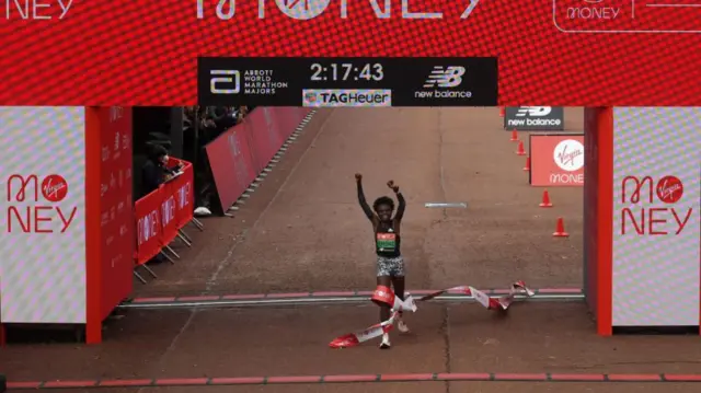 Joyciline Jepkosgei crosses the line with her hands in the air