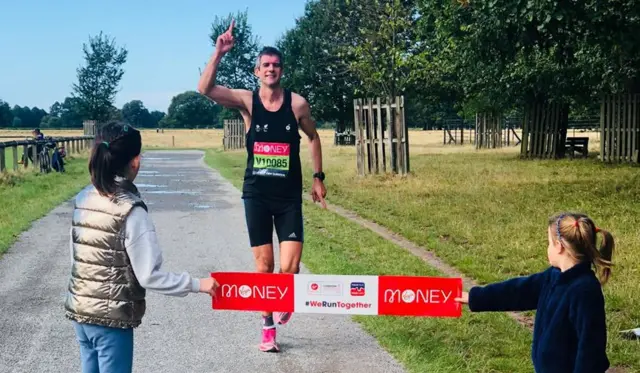 Nick Wright crosses a finish line held by his daughters