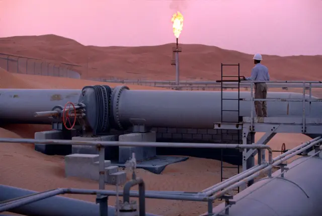 MARCH 2003: A worker stands at a pipeline, watching a flare stack at the Saudi Aramco oil field complex facilities at Shaybah in the Rub' al Khali ("empty quarter") desert on March 2003 in Shaybah, Saudi Arabia.