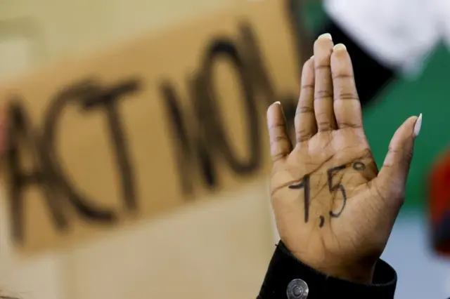 A person gestures as people protest during the UN Climate Change Conference