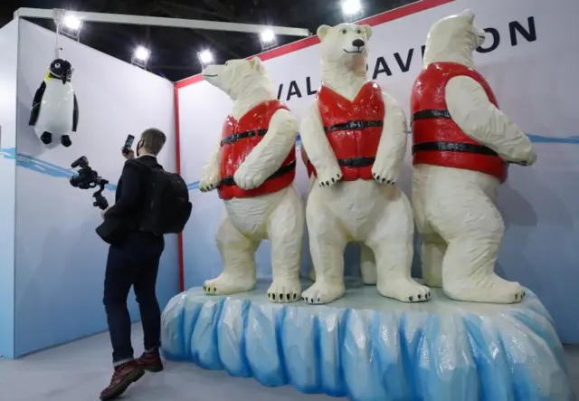 A man documents a hanged penguin representation at the Tuvalu pavilion during the UN Climate Change Conference