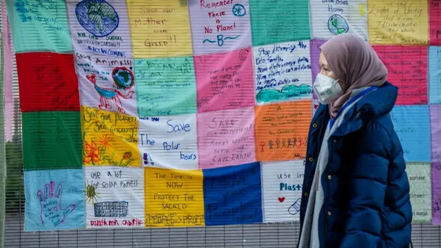 A delegate walks past climate messages on the perimeter fence outside the venue of the COP26 conference, in Glasgow, Britain, 11 November 2021.