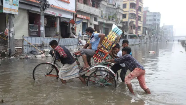 Dozens of people walk through water due to heavy rains causing flooding in Jurain District