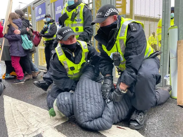 A protester is apprehended by police after trying to scale the perimeter fence of the COP26 venue