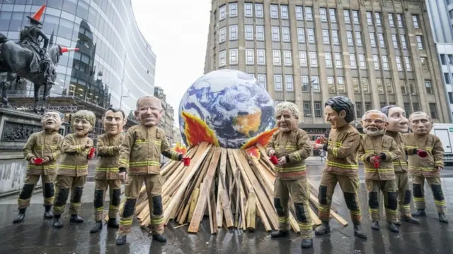 Protestors dressed as firefighters wear masks of world leaders