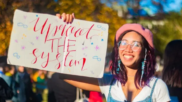 Young activist Mitzi Jonelle Tan holds up a placard saying: 'Uproot the system'