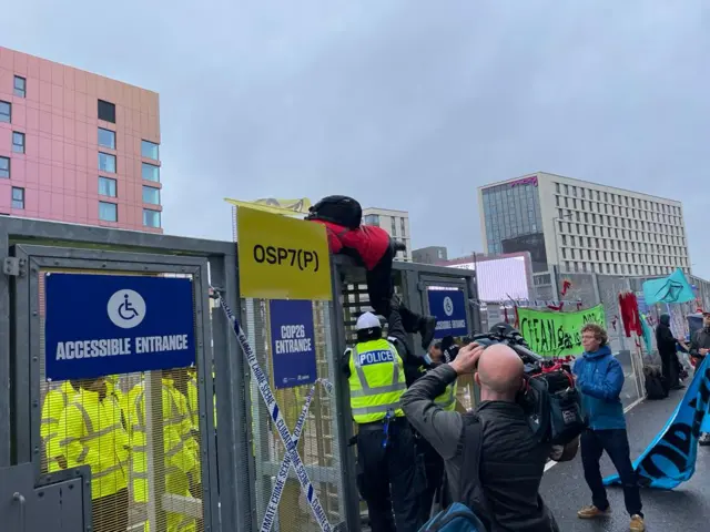 A protester scales the perimeter fence of the COP26 conference venue