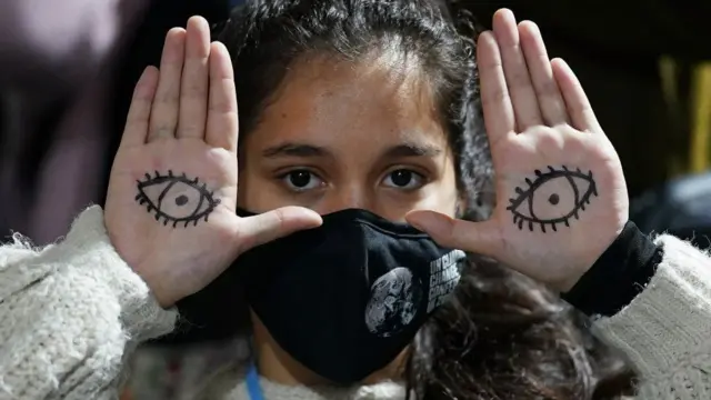 A woman protester with eyes drawn on her hands