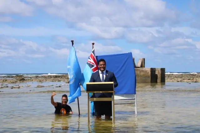 Tuvalu foreign minister Simone Kofe delivers a speech standing in the sea