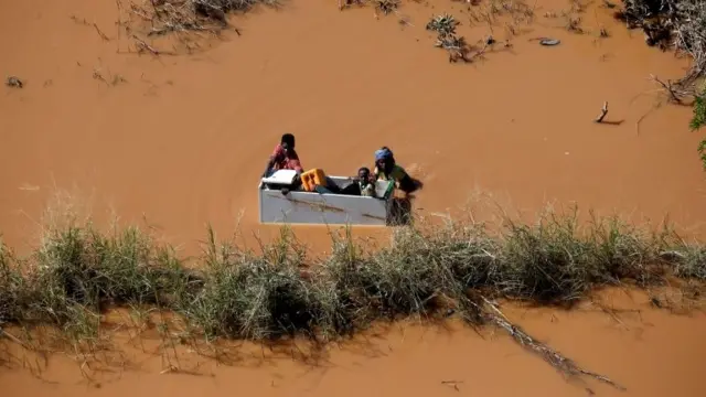 A child is transported on a fridge in floodwater in Mozambique in 2019, after Cyclone Idai