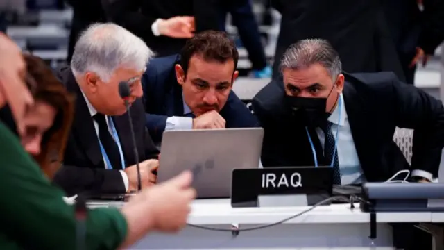 Iraqi delegates huddle around a laptop