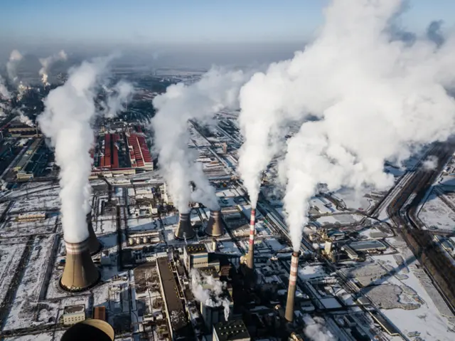 A photo of factories emitting clouds of gas.