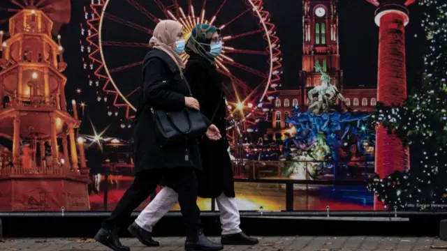 Two women wearing masks walk in Berlin, Germany
