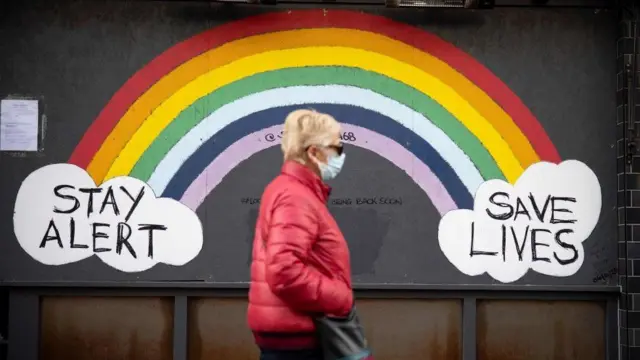 A woman walking past Covid signs