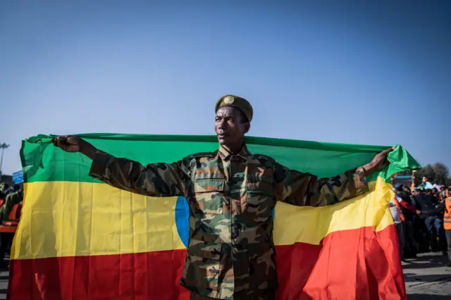 A war veteran carries Ethiopias national flag as a ceremony is held to support the Ethiopian military troops