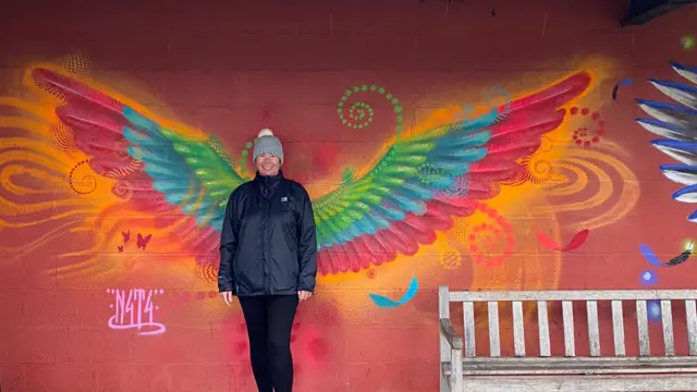 Person standing next to artwork in the trail last year