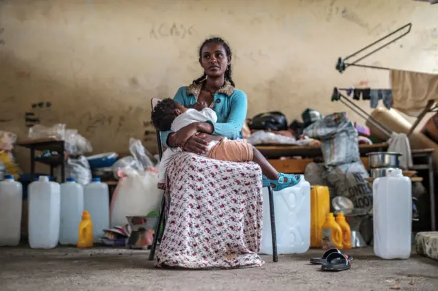 A woman displaced by fighting in northern Ethiopia breastfeeds a child in a classroom at the Addis Fana School where they are temporary sheltered, in the city of Dessie, Ethiopia, on August 23, 2021.