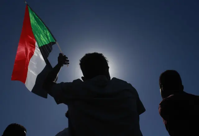 A Sudanese protester lifts a national flag during a demonstration calling for a return to civilian rule in the capital Khartoum, on November 21, 2021.