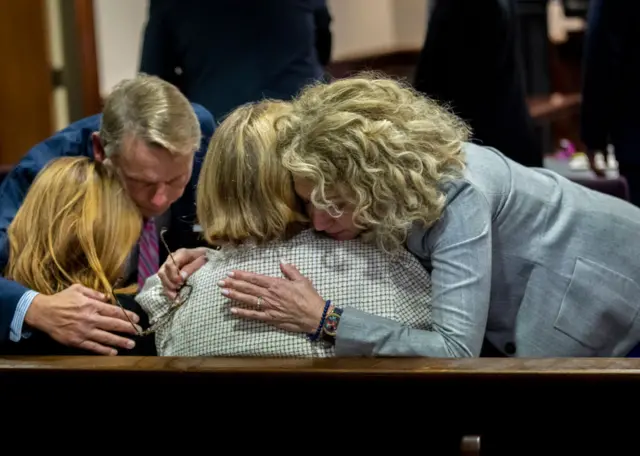 Attorney Laura Hogue, right, hugs Greg McMichael's wife Leigh McMichael, center, and his daughter Lindsey McMichael