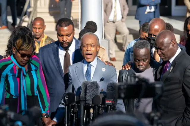 Rev. Al Sharpton, center, with Wanda Cooper-Jones, mother of Ahmaud Arbery, left, attorney Lee Merritt, second from left, attorney Ben Crump, right, and Marcus Arbery, father of Ahmaud Arbery, leads a prayer outside the Glynn County Courthouse as the jury deliberates