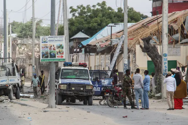 Police officers and people stand at the bomb explosion site in Mogadishu, Somalia, on November 25, 2021.