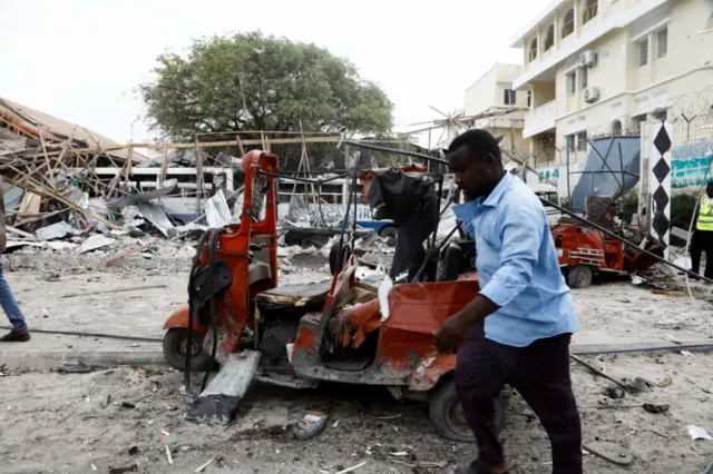 A civilian walks past the wreckages of vehicles and the debris of classrooms after a car exploded in a suicide attack near Mucassar primary and secondary school in Hodan district of Mogadishu, Somalia November 25